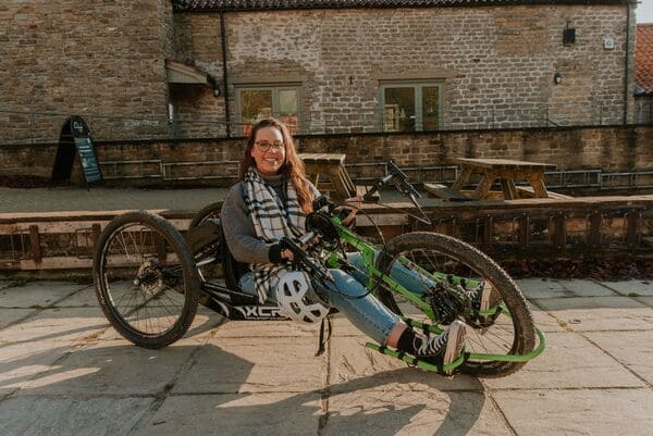 Jennie, brunette with glasses, sat on disability friendly bike.