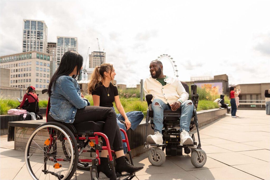 Three friends wait outside of the theatre for their show to start. The friends come from diverse backgrounds and the image demonstrates intersectionality. American Express