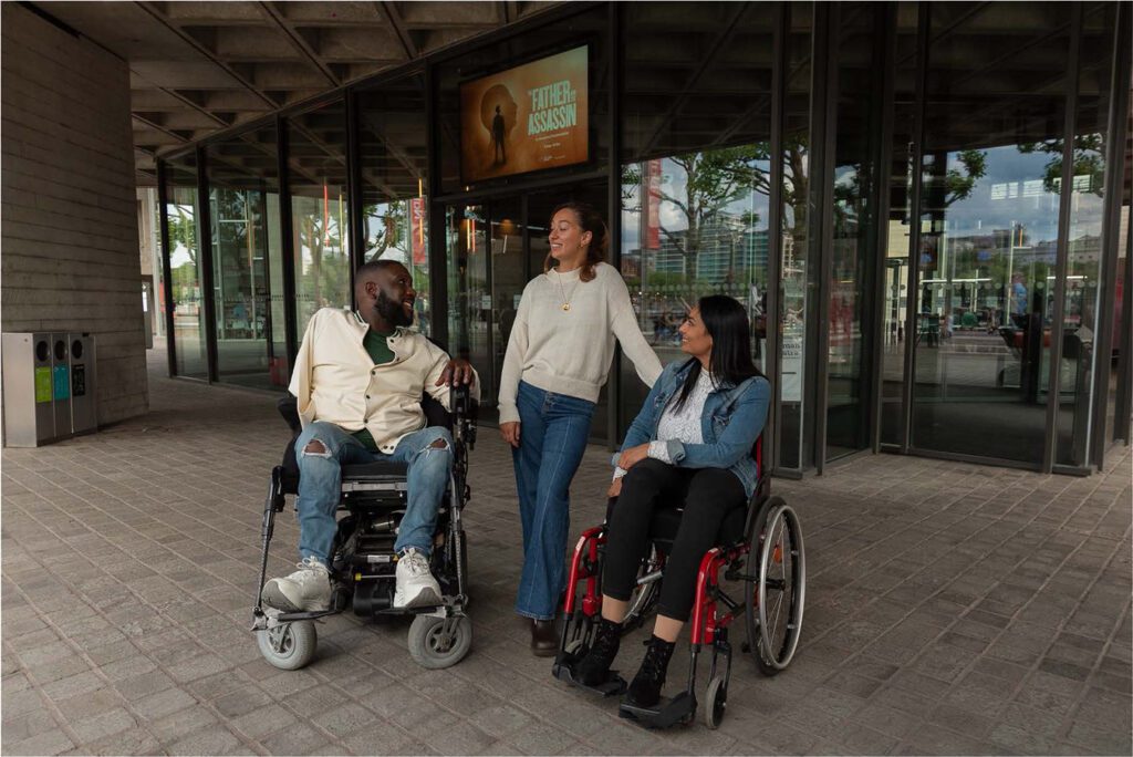 Three friends are about to enter a theatre to watch a show together. The friends come from diverse backgrounds and the image demonstrates intersectionality. American Express