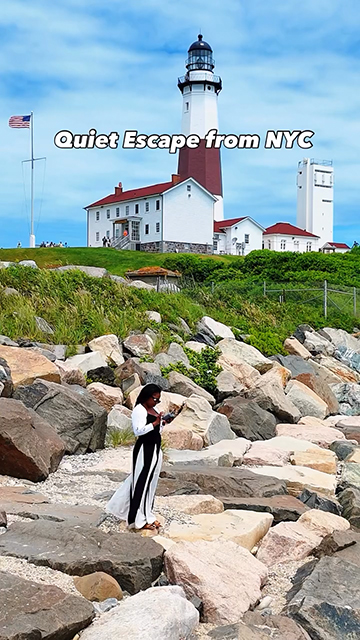 For U.S. Lighthouse Society Campaign, Woman stands on a rocky, coastal foreground in front of a lighthouse.