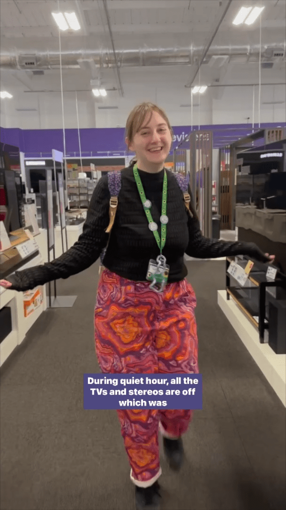 Screenshot of a woman walking through the aisle of a Currys store with her arms outstretched. Text at the bottom reads: "During quiet hour, all the TVs and stereos are off which was."