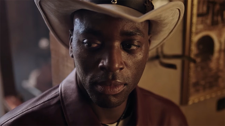 A man in a cowboy outfit in a wild-west saloon, representing the "no," aspect of the "Low. Slow. No," trio.