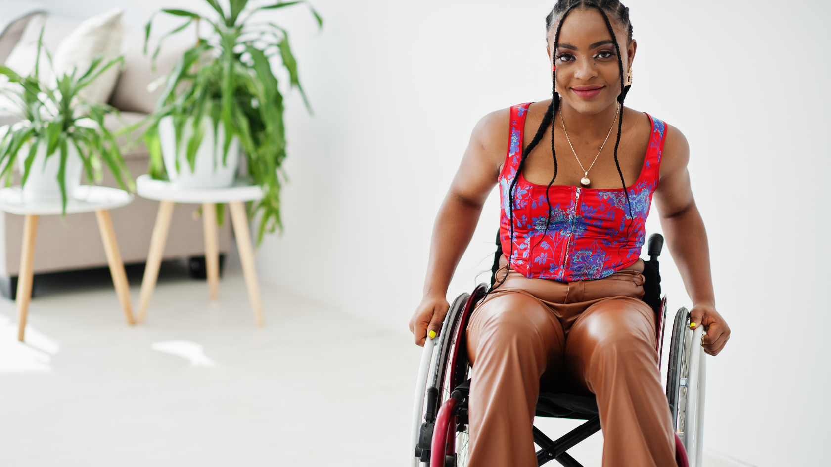 A female manual wheelchair user is in a living room, smiling to the camera.