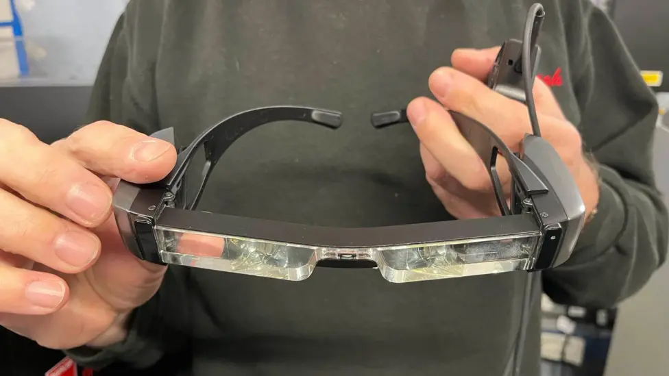 Close-up of the subtitle glasses being held by someone.