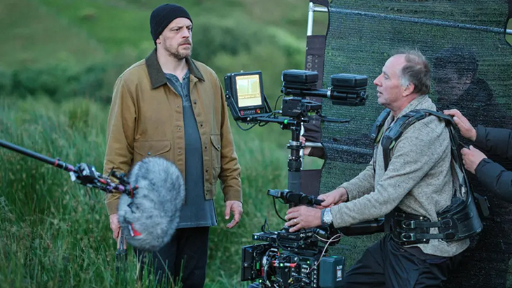 Behind-the-scenes production shot of the filming of 'Reunion' outside in a field.
