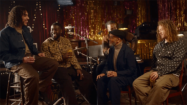 A scene from the Courvoisier advert. A group of men sit in a pub with drinks, chatting and laughing.