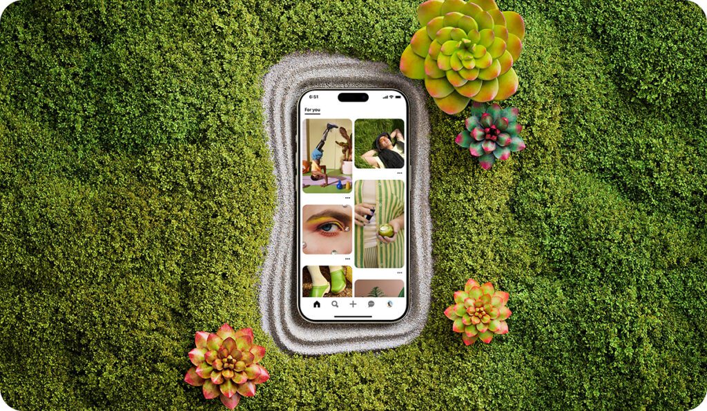 A phone showing a Pinterest Board sits in a verdant green zen garden.