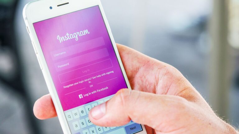 Someone holding a phone in their handing, typing in their Instagram login details.