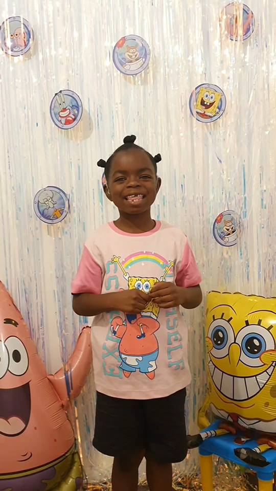 For Paramount campaign, a small girl smiles in front of a Spongebob themed wall while wearing Spongebob adaptive wear.