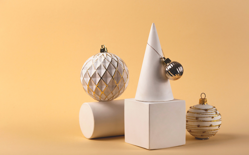 Shapes and white Christmas baubles in a neutral product photo setup.