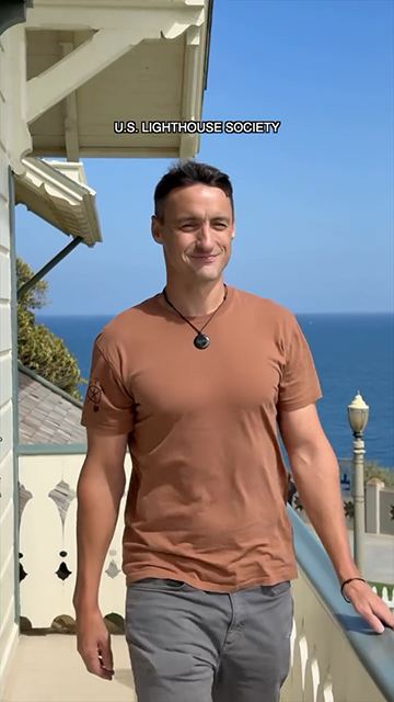 For U.S. Lighthouse Society Campaign, Man walks on the outside space around a lighthouse building.