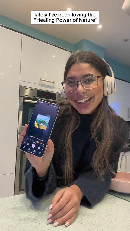 Prisha is in the kitchen holding her phone to the camera, showing us the latest audiobook she is listening to on Audible.