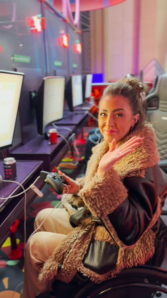 A female wheelchair user waves to the camera as she plays a computer game at Virgin Media's new Gamepad location.