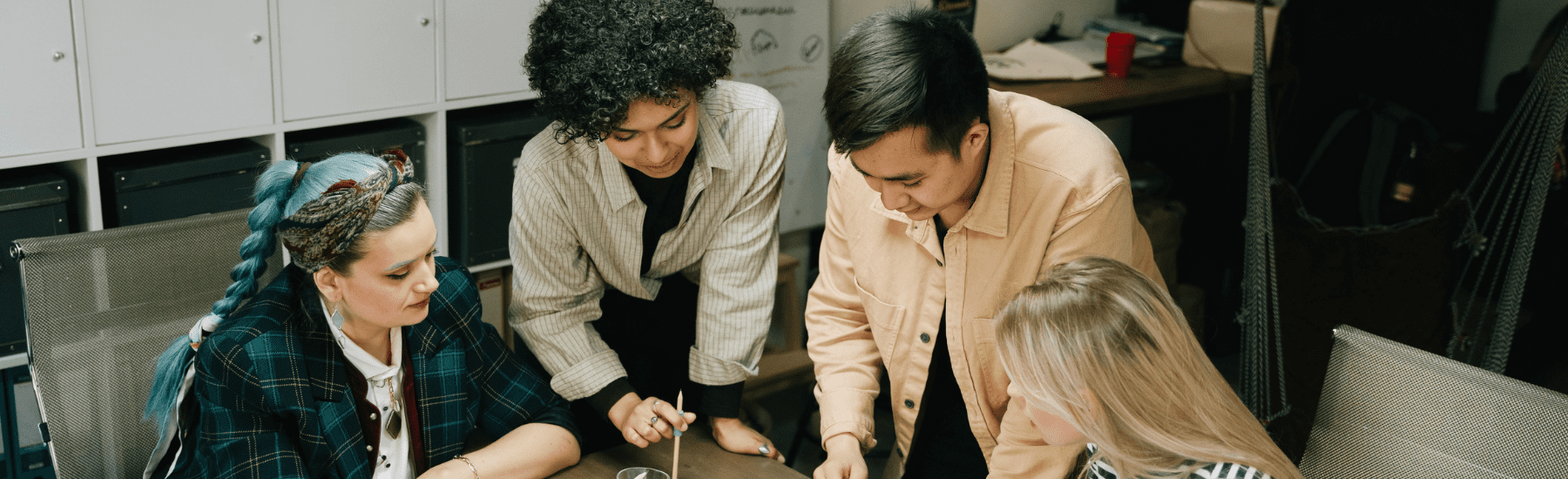 Four people of various ethnicities sat around a table discussing ideas.