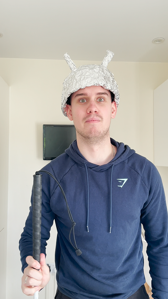 Toby holds a cane and wears a tin foil hat, pondering how a blind man can become an astronaut.