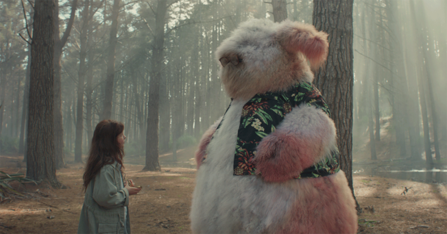 An image from the Apple's ad, showing a girl with a big fluffy creature in a forest.