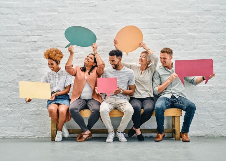 A diverse group of people holding illustrative cutout speech bubbles.