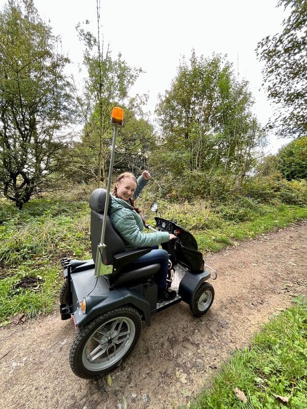 Girl in wheel chair on a moorland track celebrating