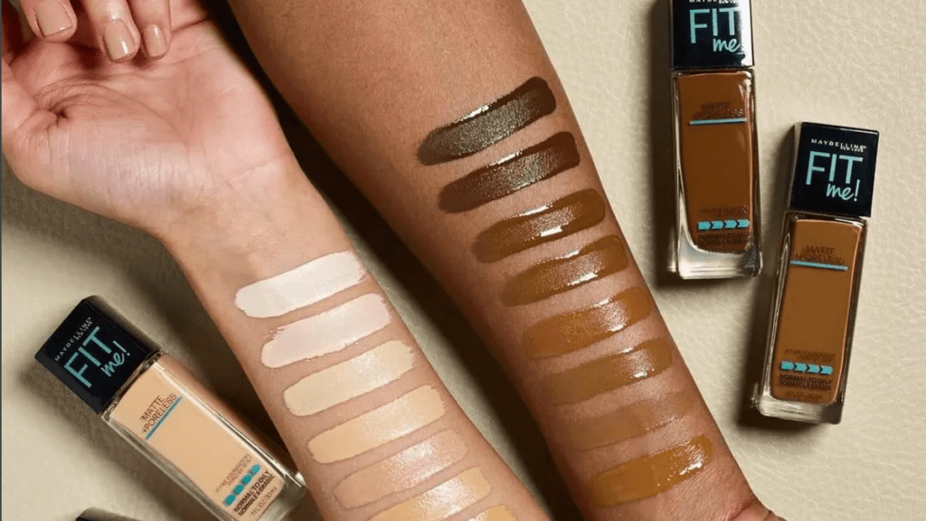 An image of two arms, one from a white person, and the other from a black person, showcasing some of the different shades available for the 'FIT me' Maybelline foundation.