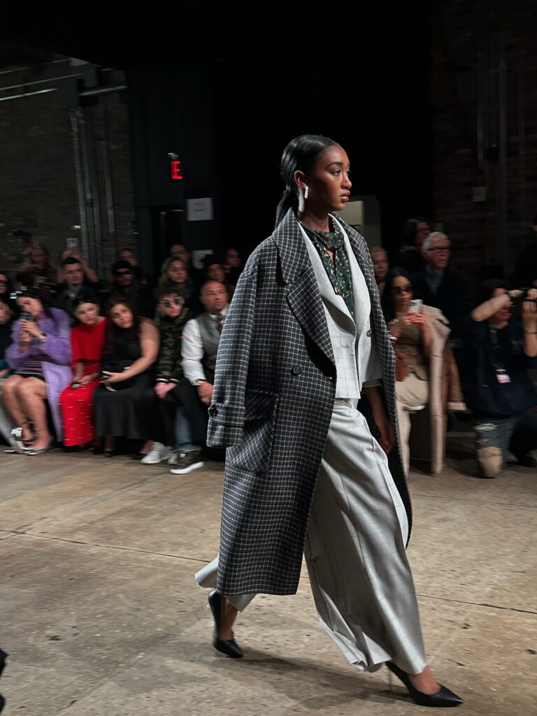 A model is walking down the catwalk at a fashion show.