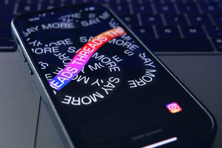 A smartphone resting on a laptop. The phone is on the Threads app.