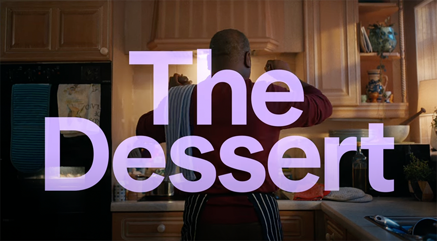 An image from one of the Starling Bank's ads showing a black man from behind, cooking and dancing in the kitchen. There is a big title on screen that says 'The Dessert'.