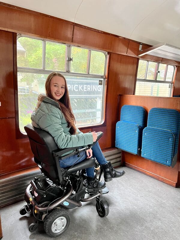 Girl sat on train in a wheelchair smiling